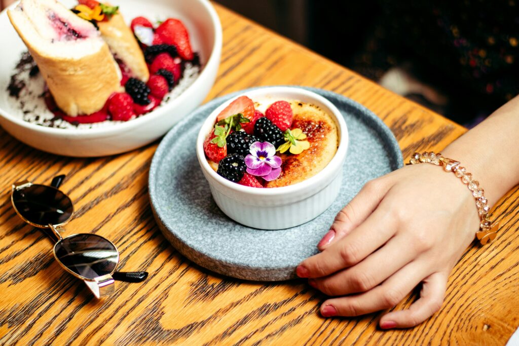 Close-up of crème brûlée topped with fresh berries and a flower, perfect for food lovers.